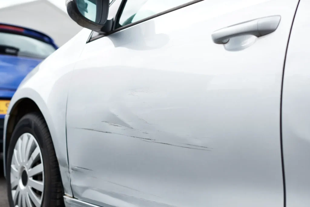 A white car with a scratch across the side of it. 