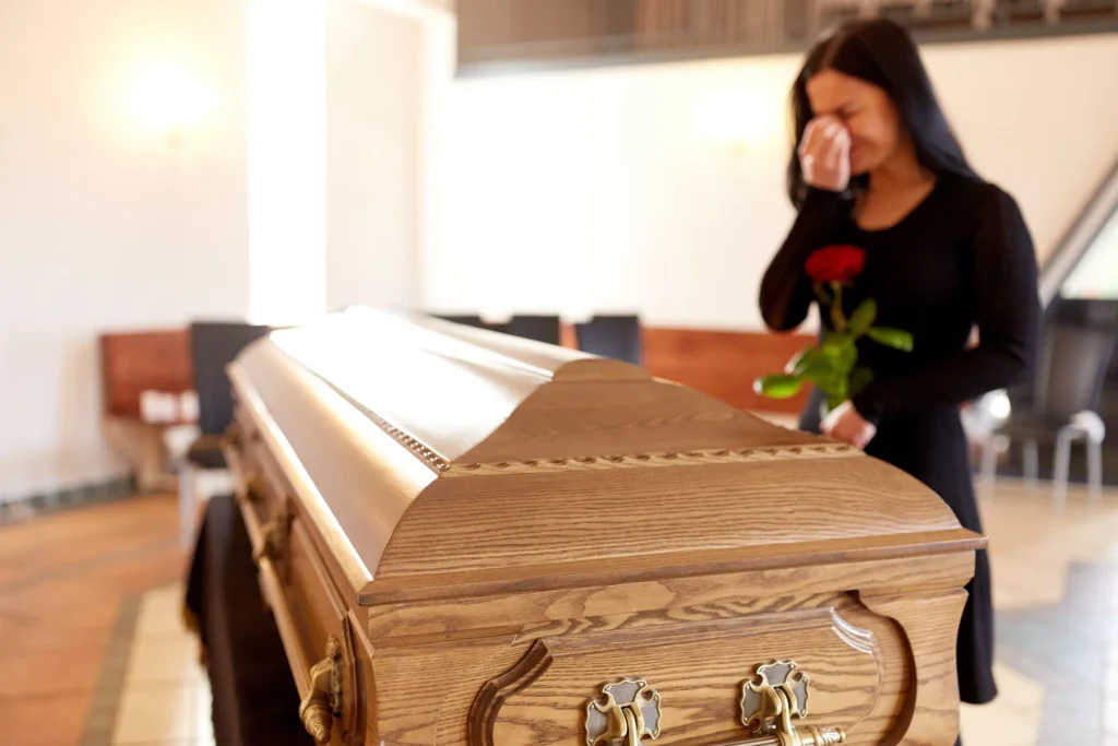 A woman crying over a coffin with a rose.