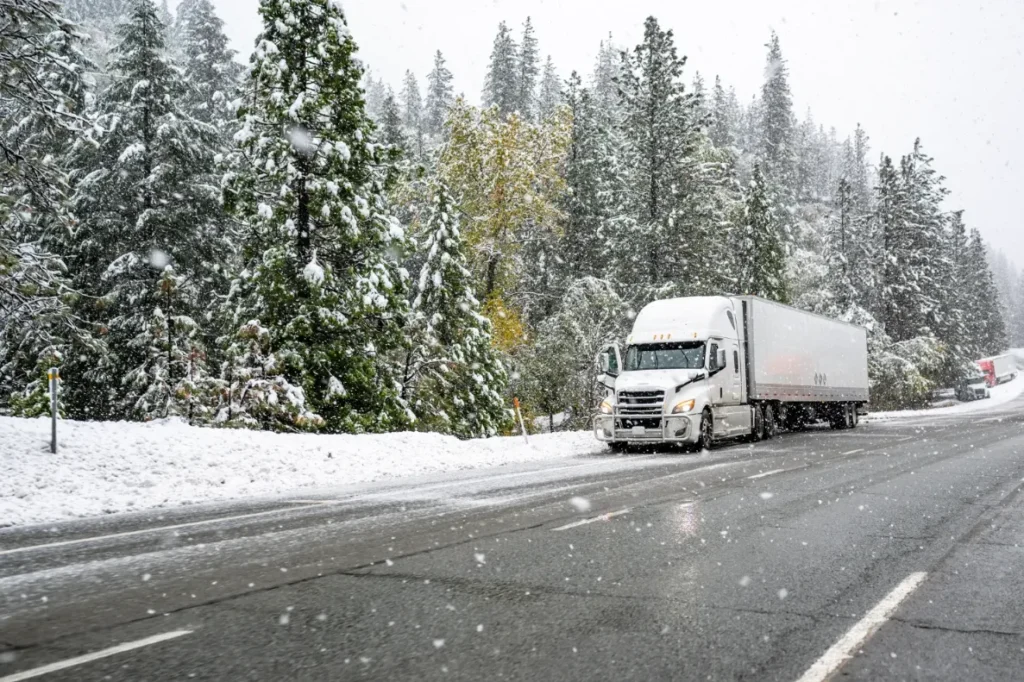 A truck driving on the highway in the snow.