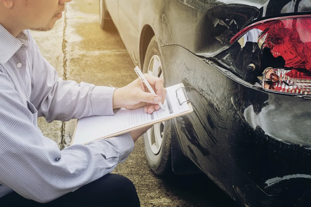 An insurance adjuster looking over a damaged car.