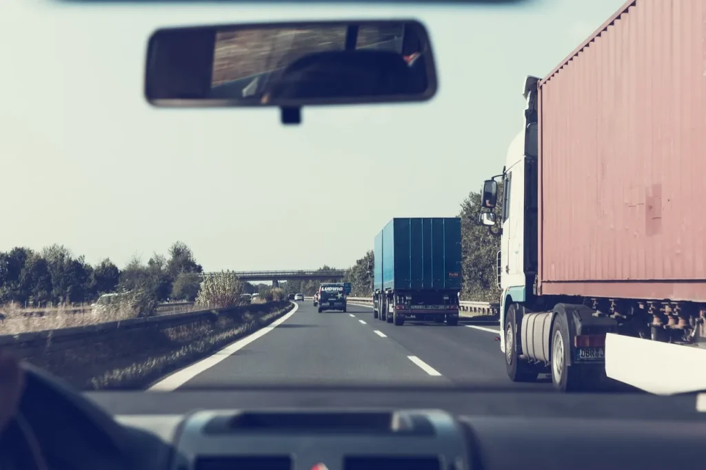 A car driving next to a truck on a highway.